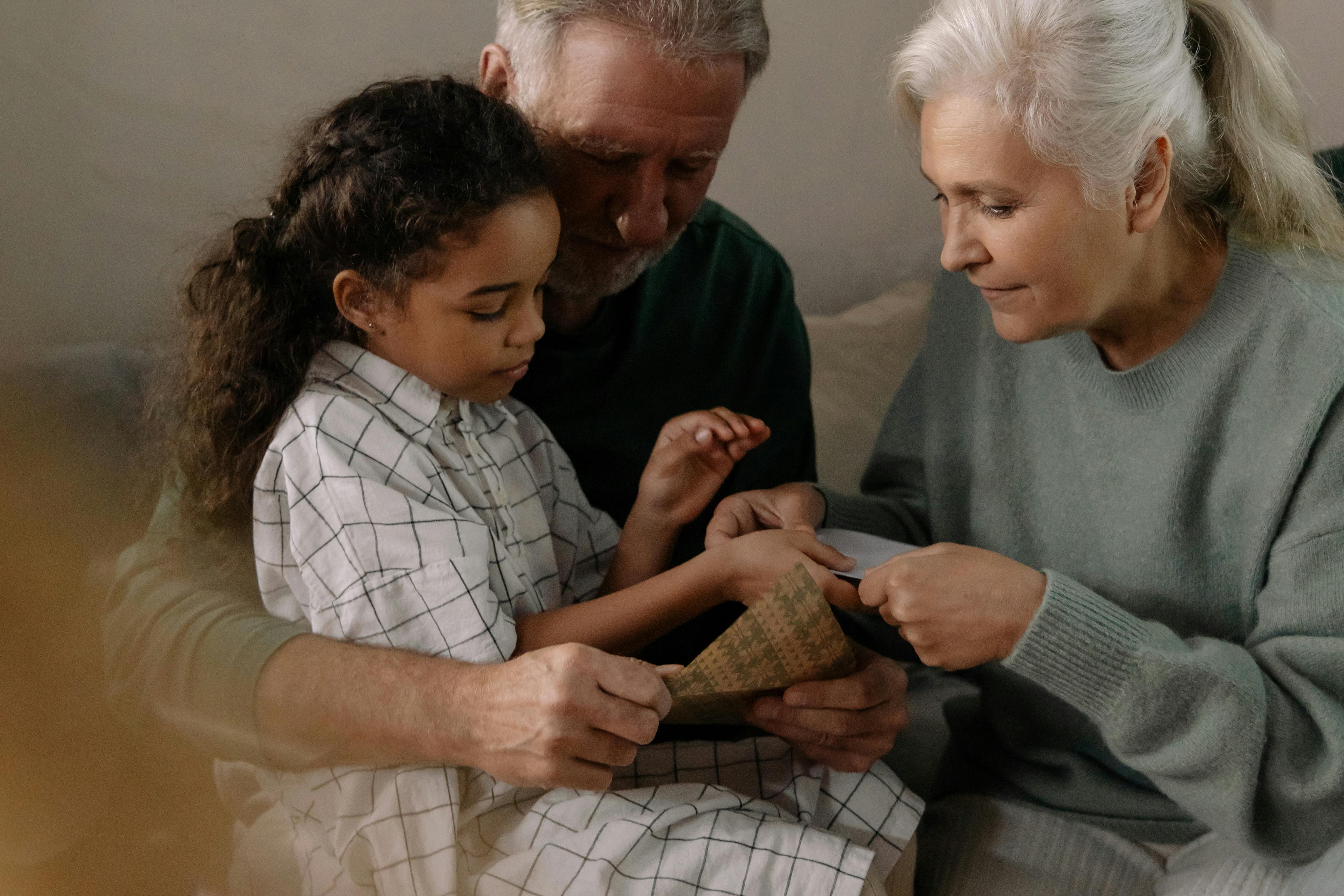 Grandparents bonding with their granddaughter over a cherished family photo indoors.